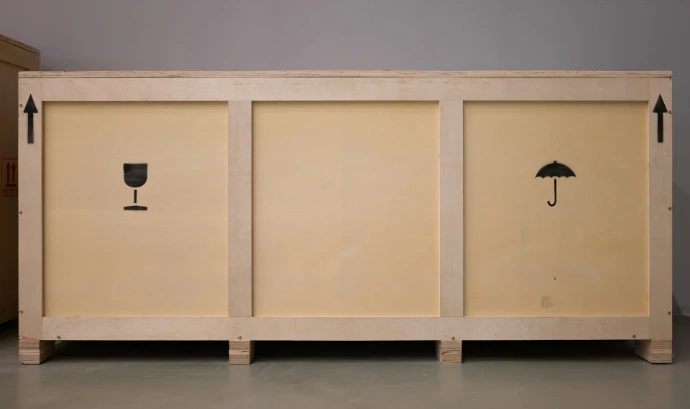 A large wooden crate with shipping symbols.